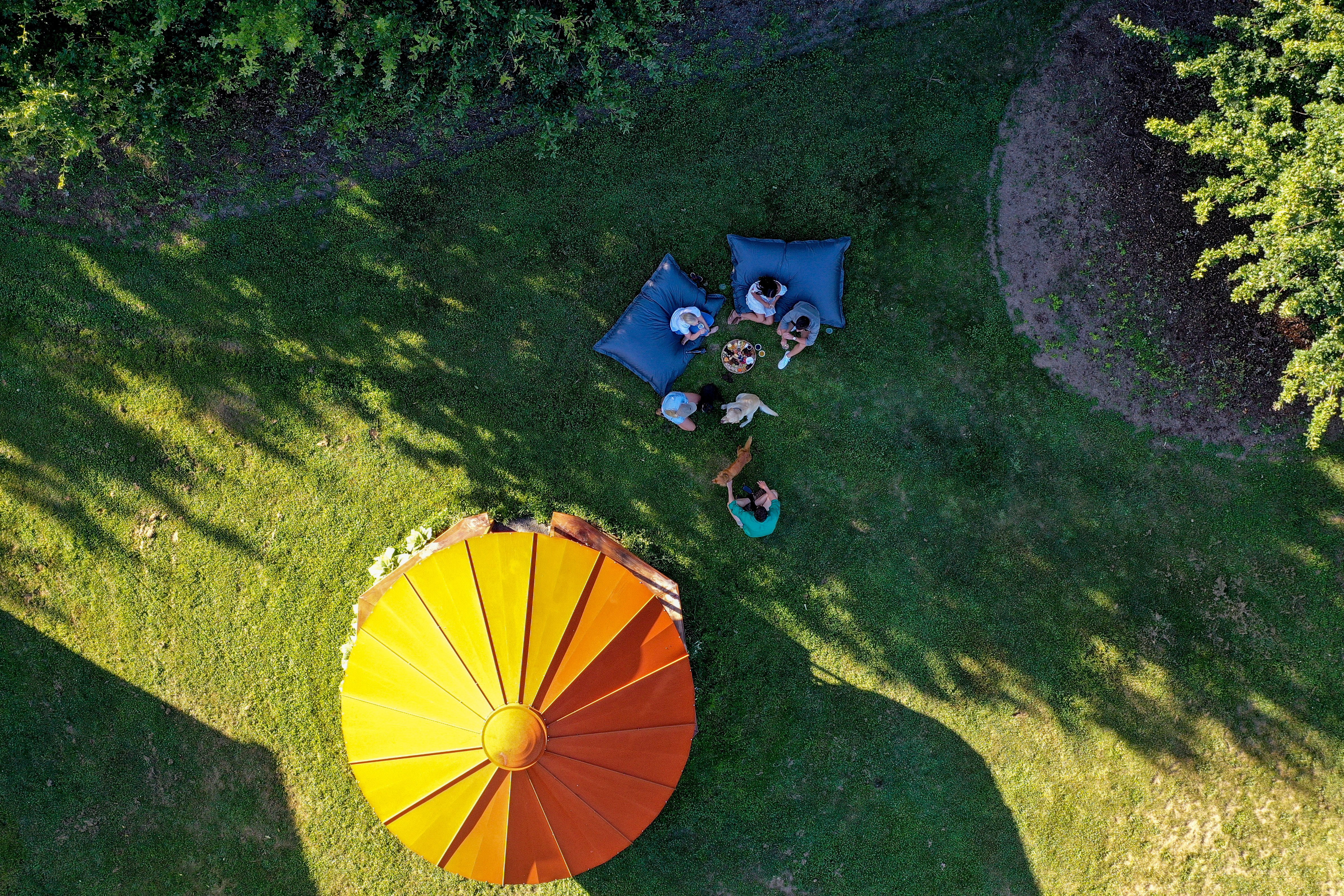 Picnic makers sitting under an umbrella in a farm