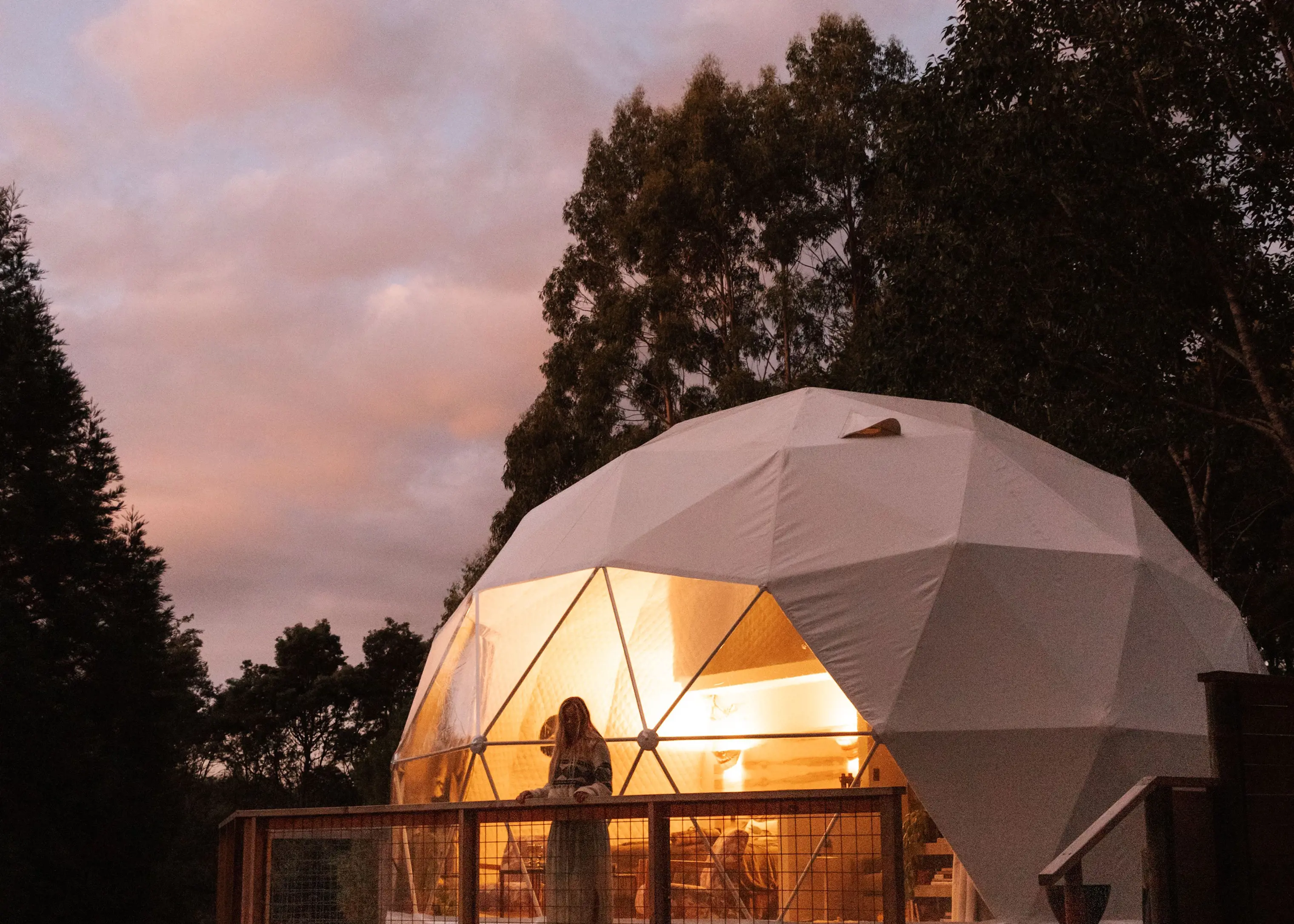 Women looks out from bell tent as the sun sets 