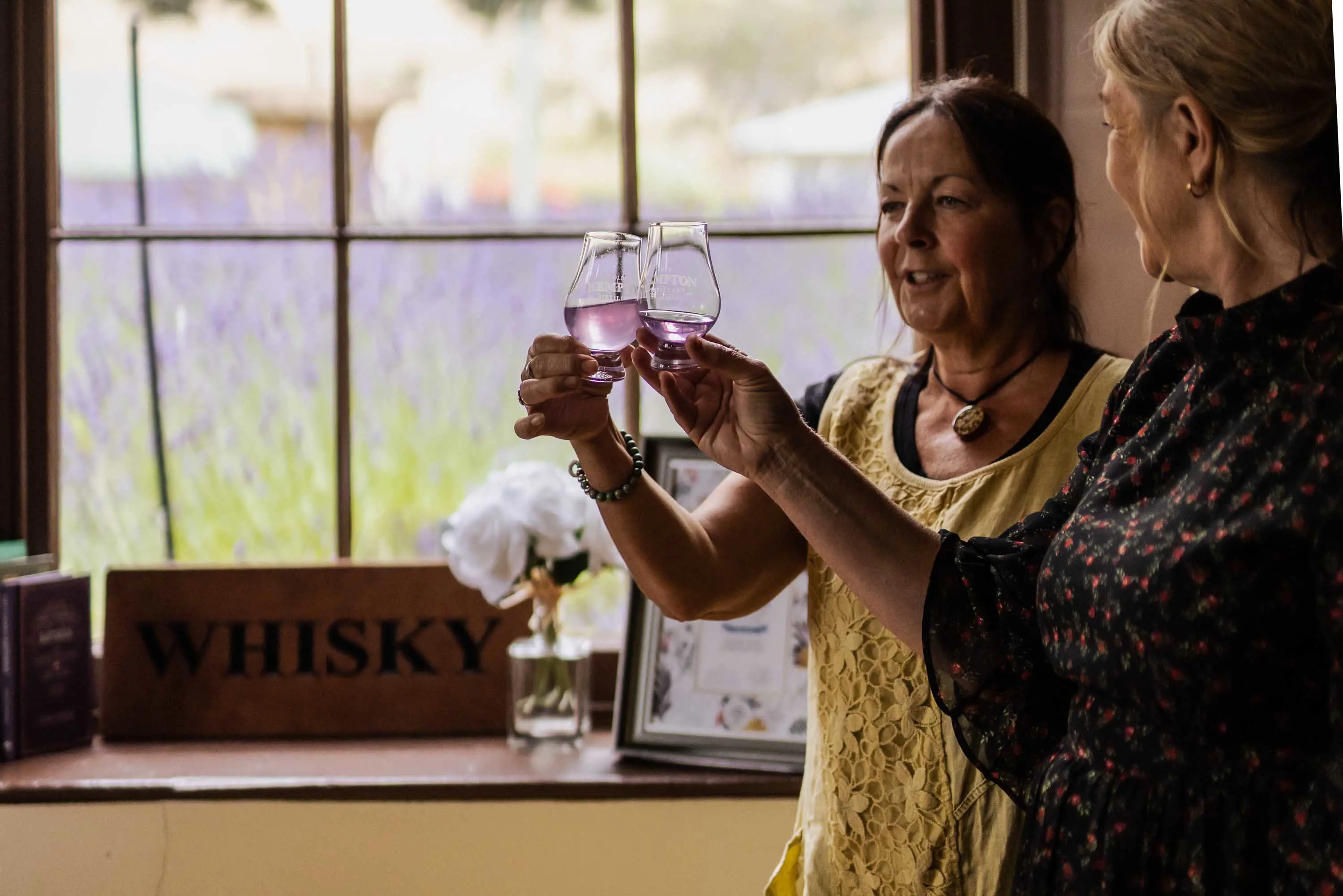 Two women clink their glasses together 