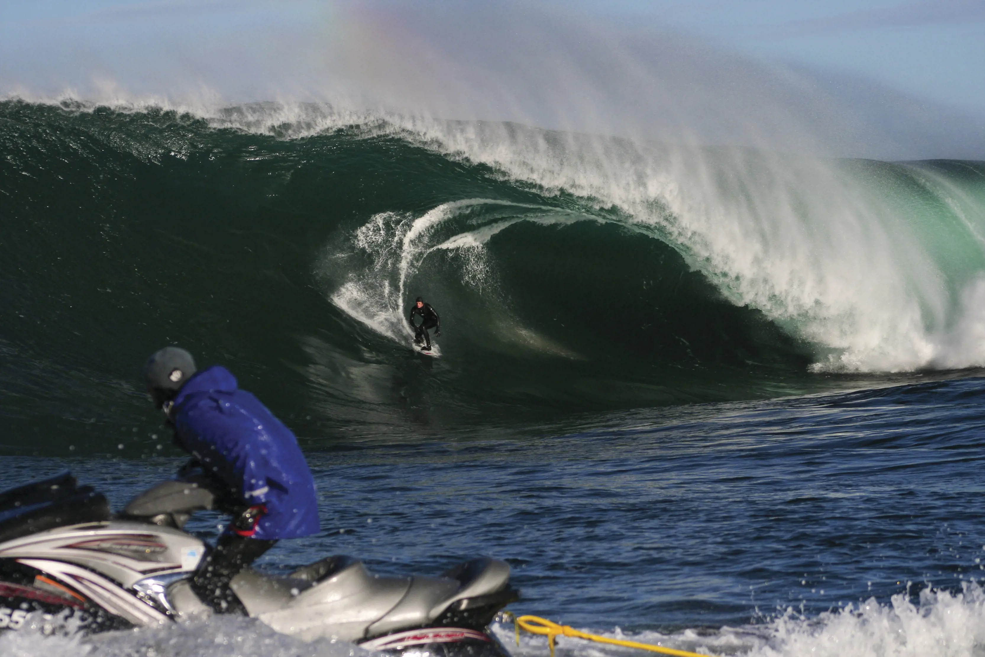 Person on a jet ski watching a surfer catch a wave at Shipstern Bluff, Turrakana / Tasman Peninsula.