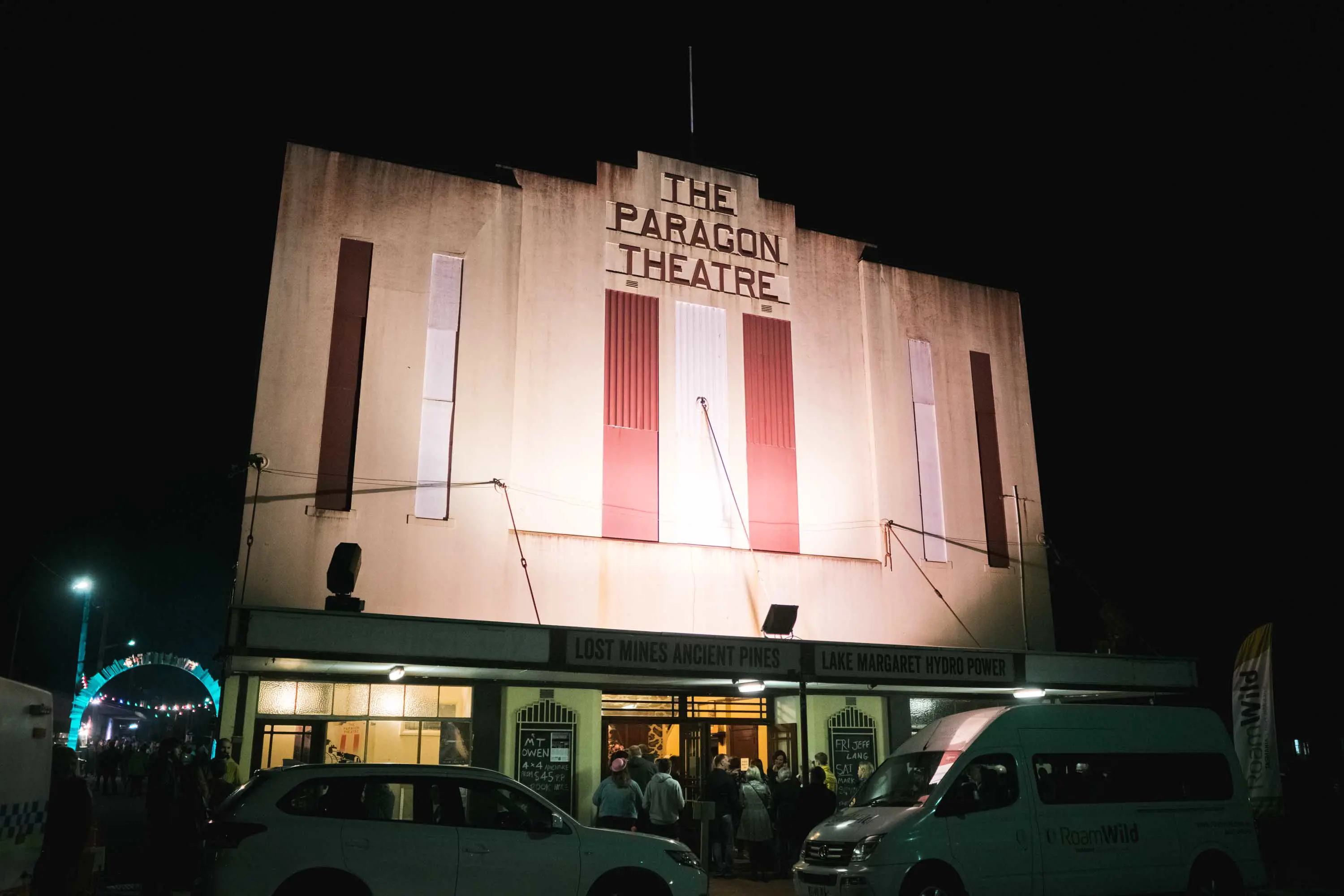 A tall pale coloured art deco style building at night lit from below.