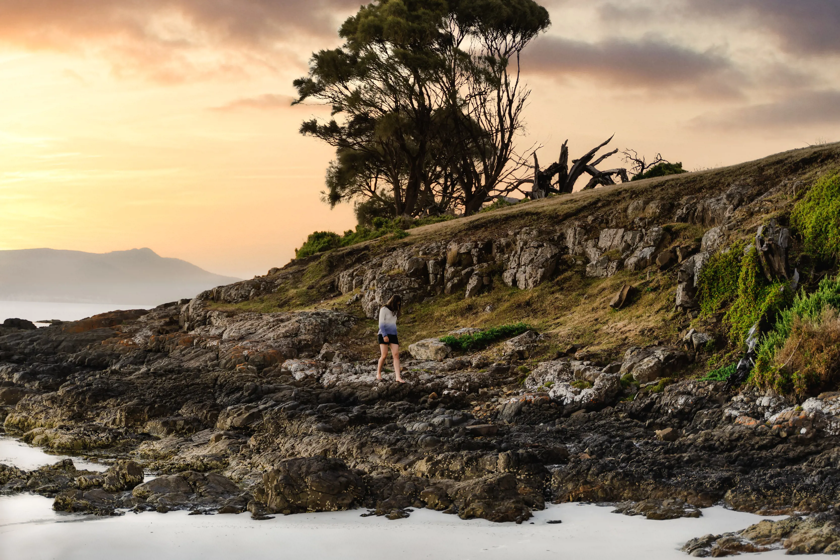 A person walks along the rocks at Booming Bay, Maria Island National Park