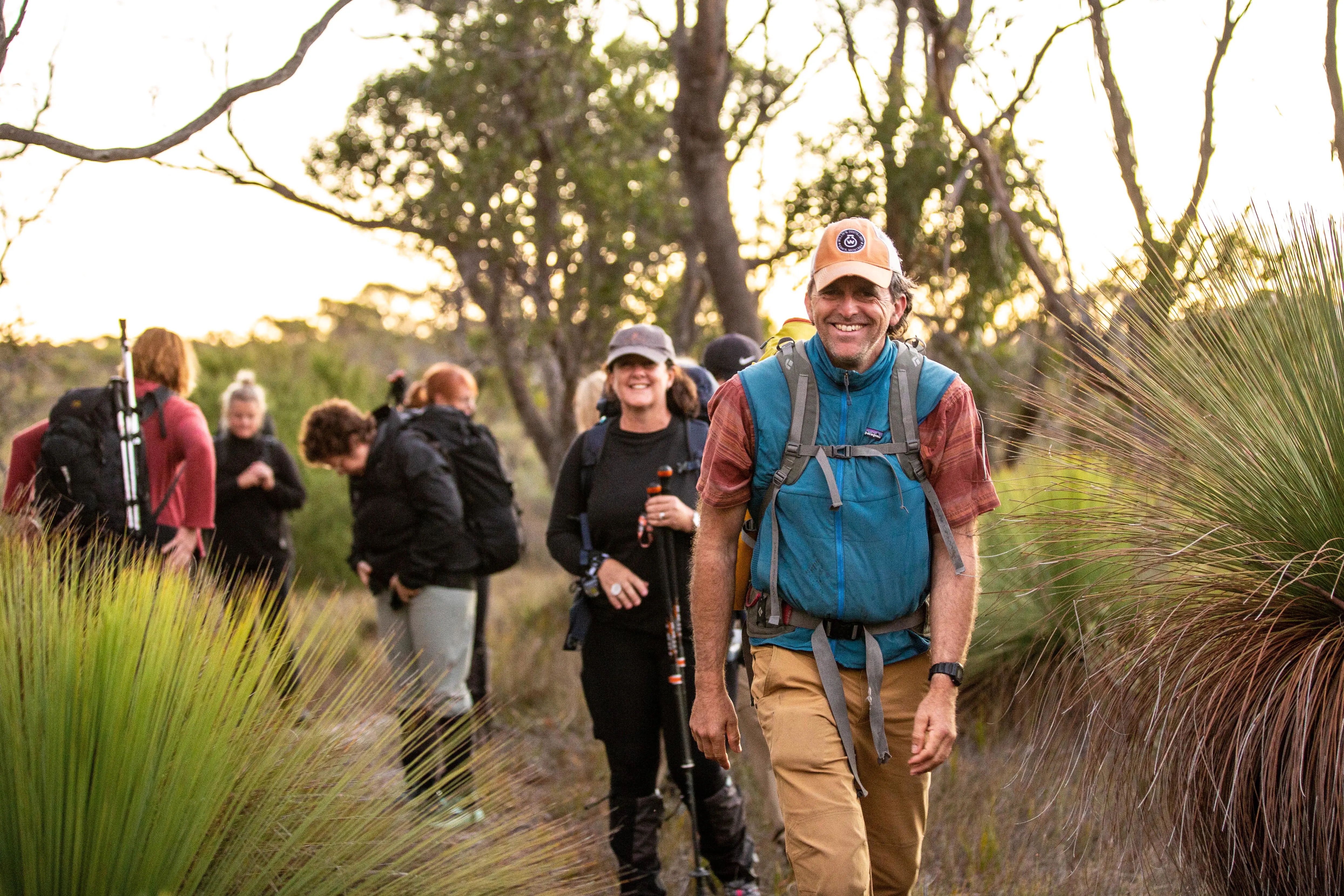 A group of a people walk along a track that winds through tall grass.