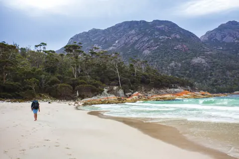 A person walks across the empty beach, Freycinet National Park