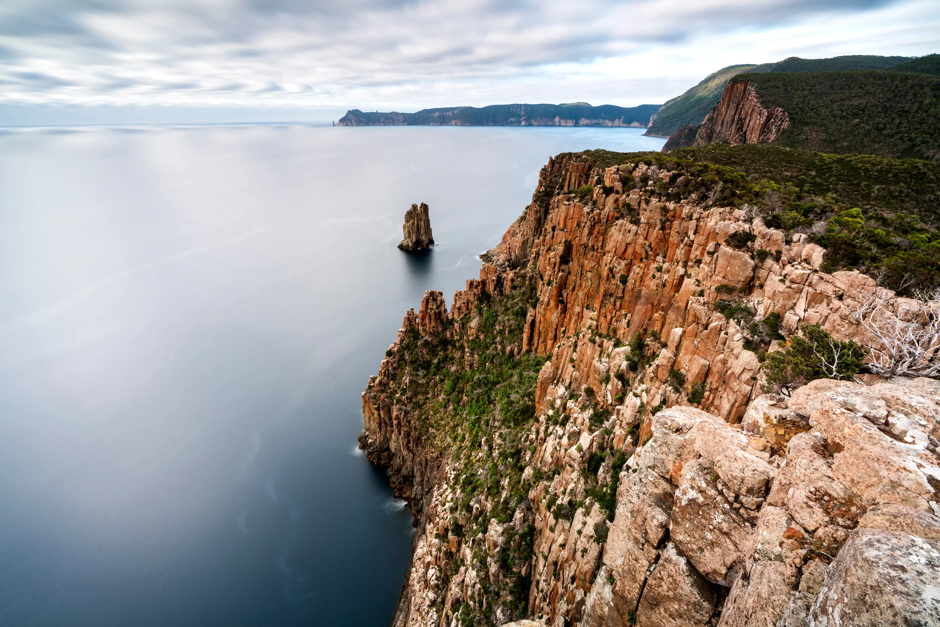 A steep, rocky cliff with blue waters below.