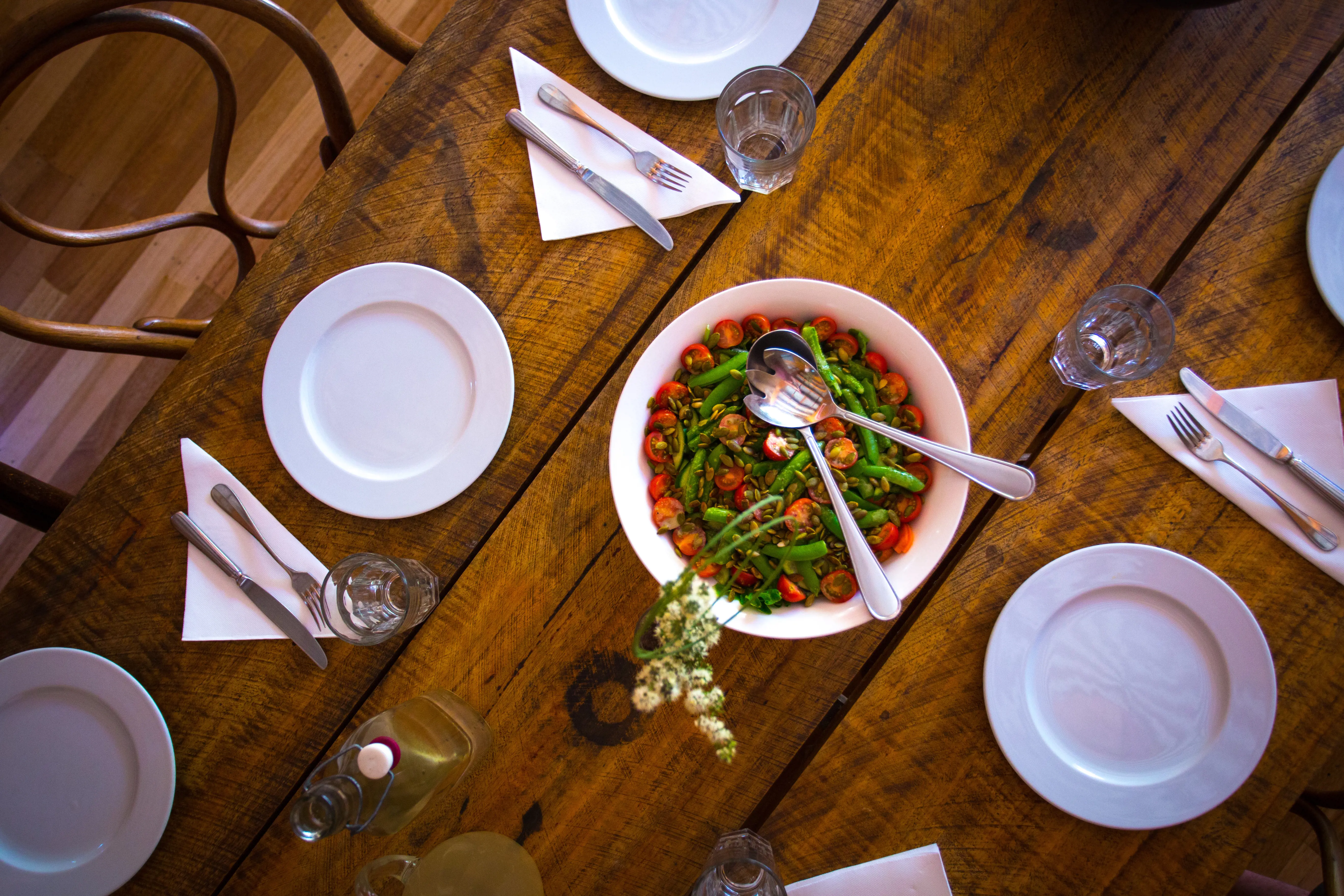 Wooden table, set for lunch with a plate of sauted vegetables