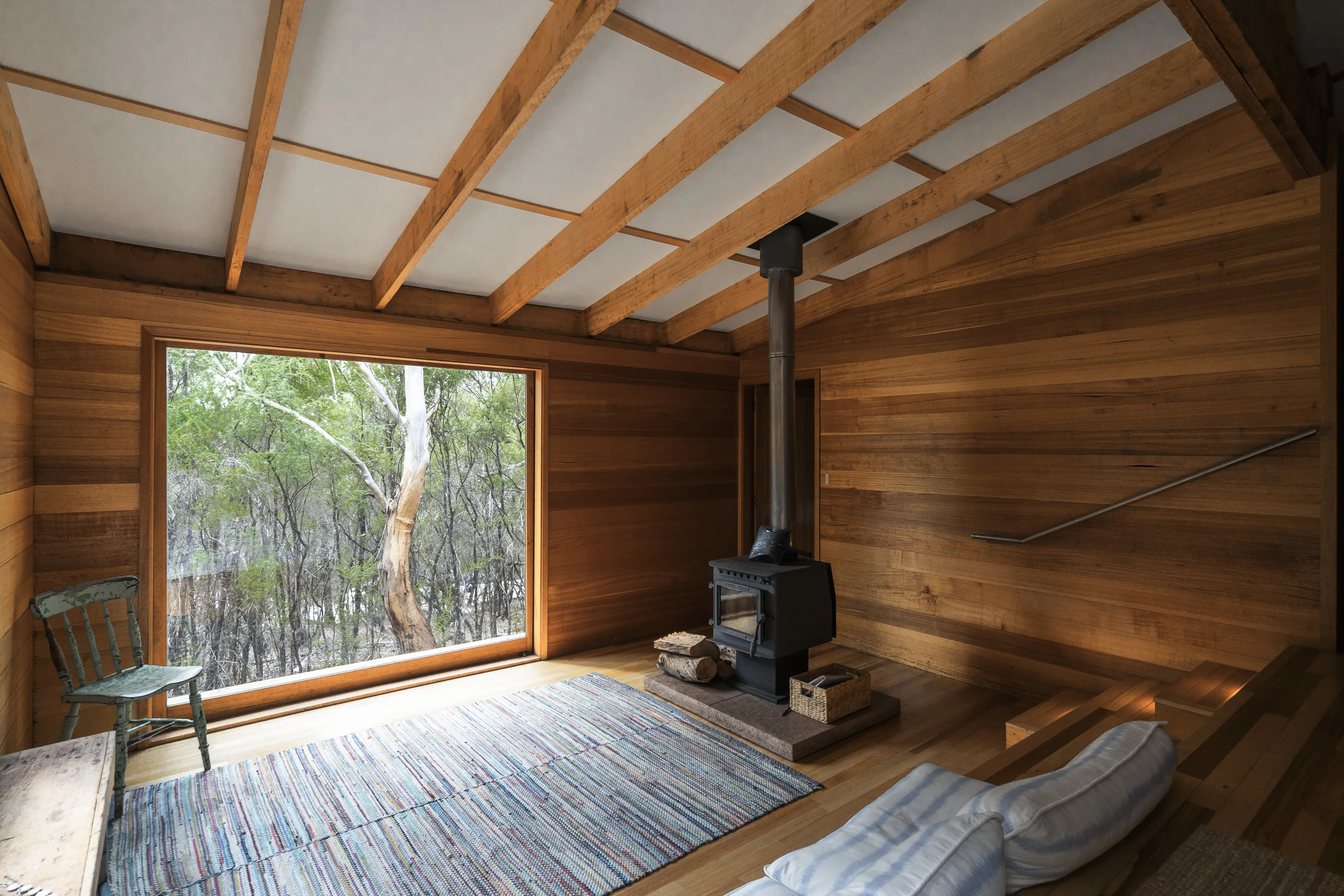 Wooden lodge interior with a fireplace and large window.