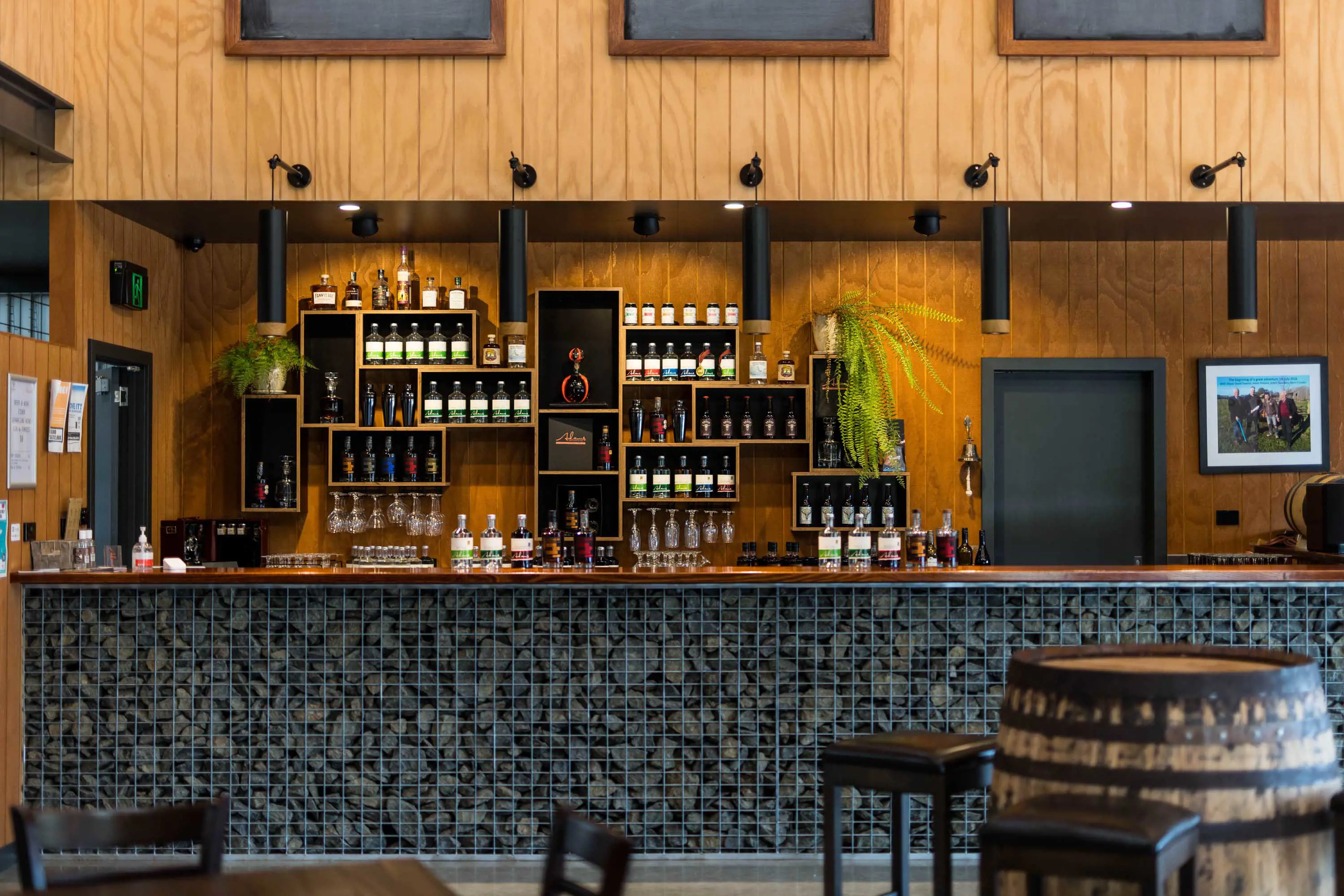 A stylish bar with wood ceilings, down lights and blue stone encased in wire.