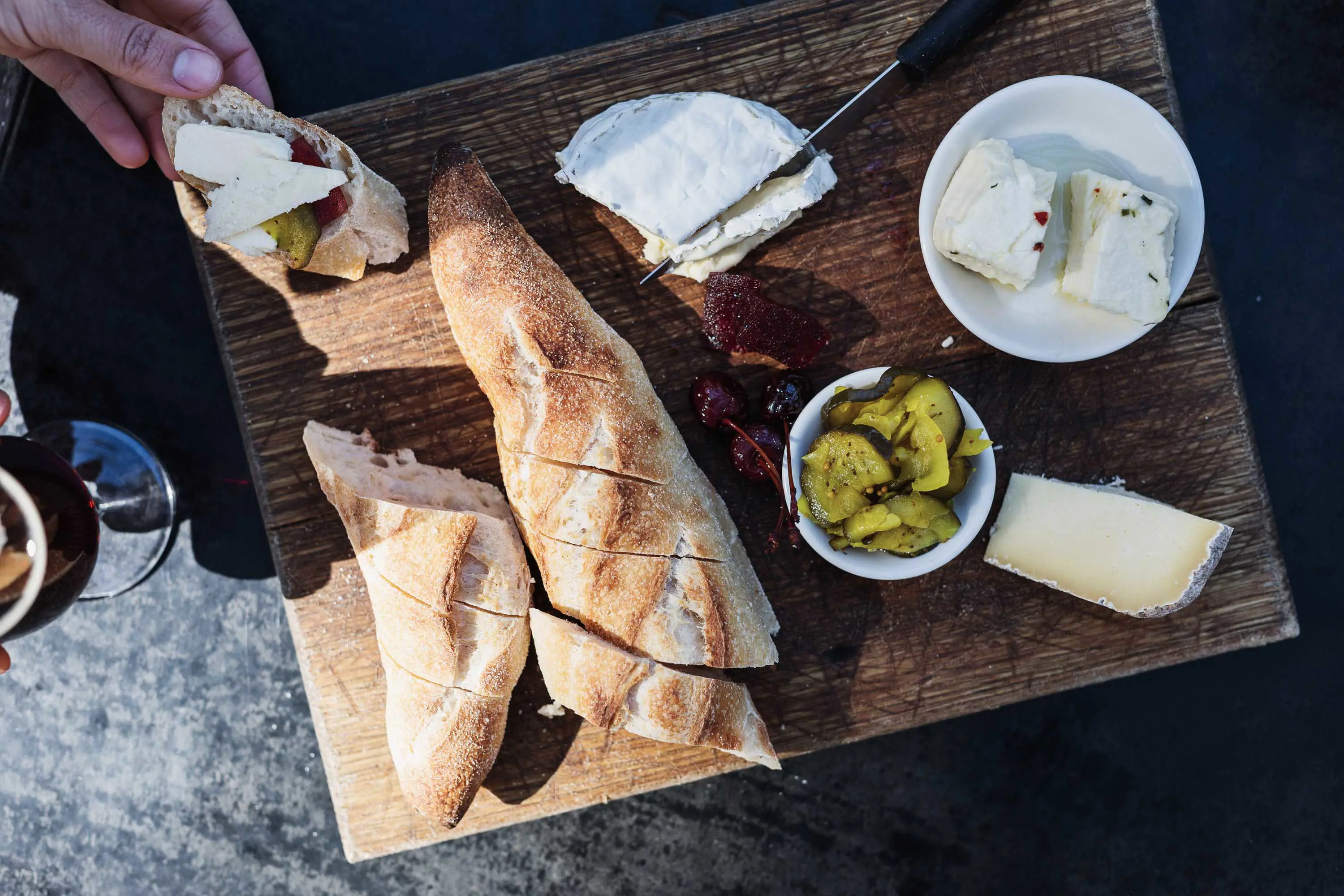 Bread, cheese and pickles placed on a large wooden board.