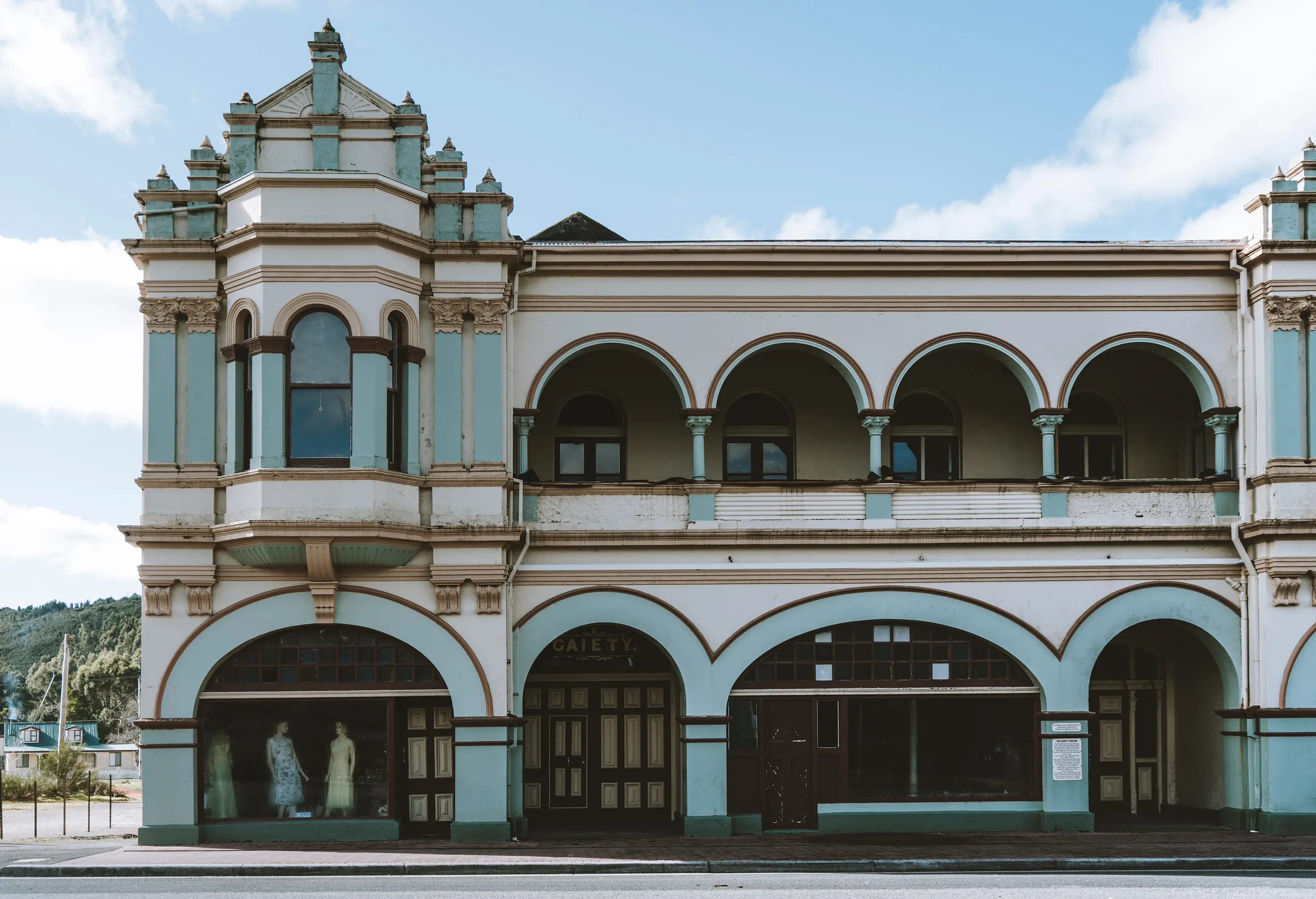 A old, two-storey building with art-deco style arches and spires, stands on the corner of a street.