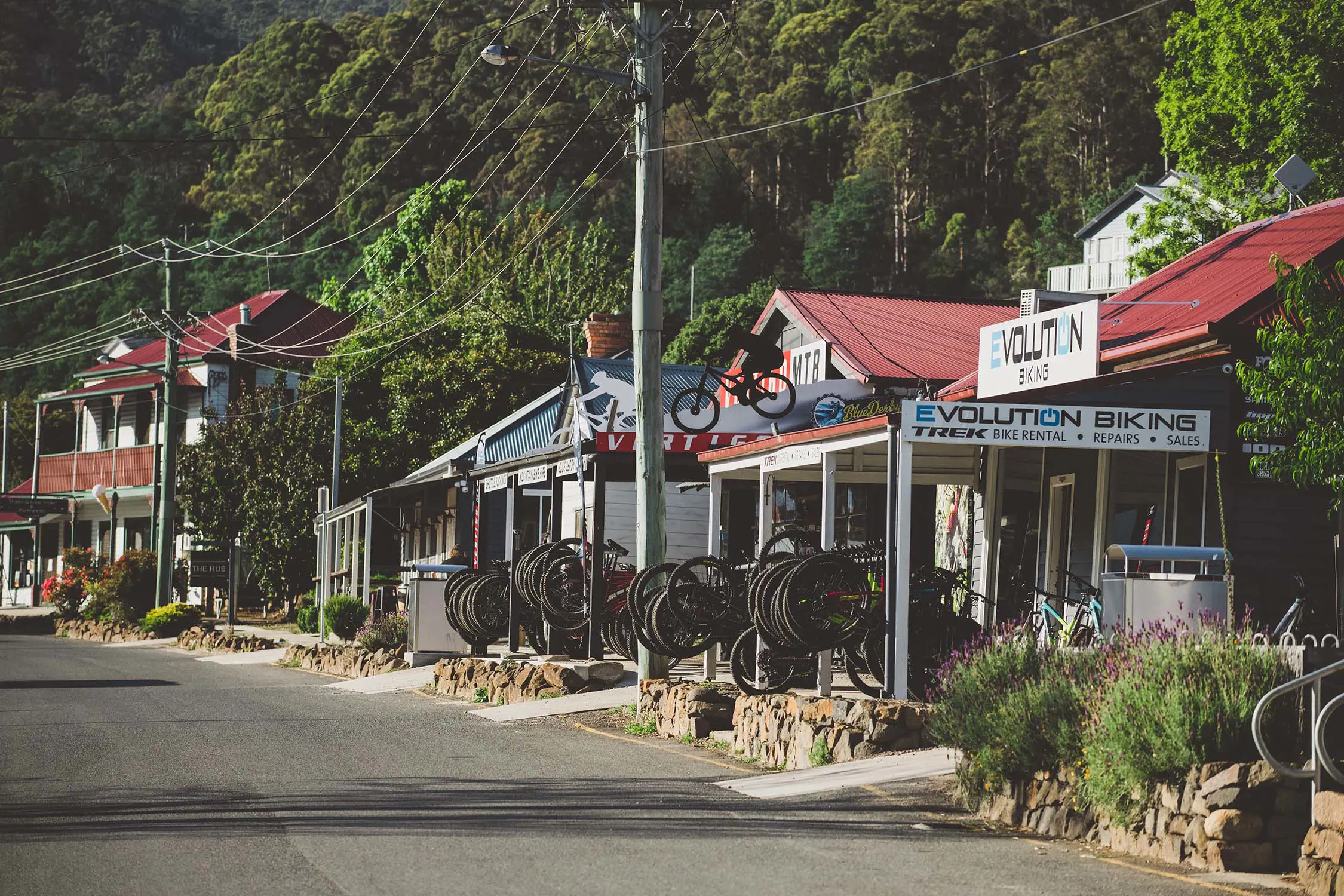 The side of a main road of a country town with several shops, including a bike shop called Evolution Biking. There are rows of bikes out the front.