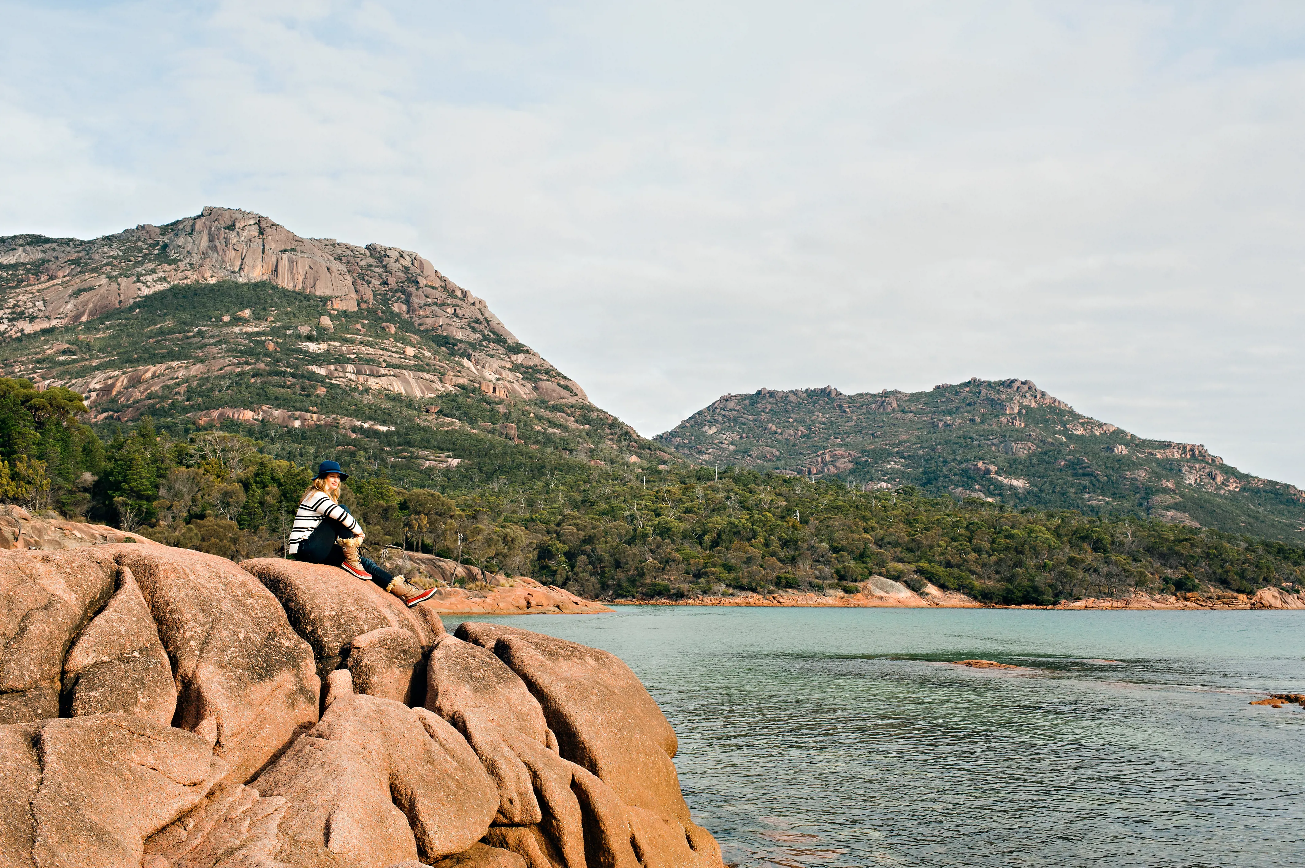 Women sitting on granite outcrop overlooking bay