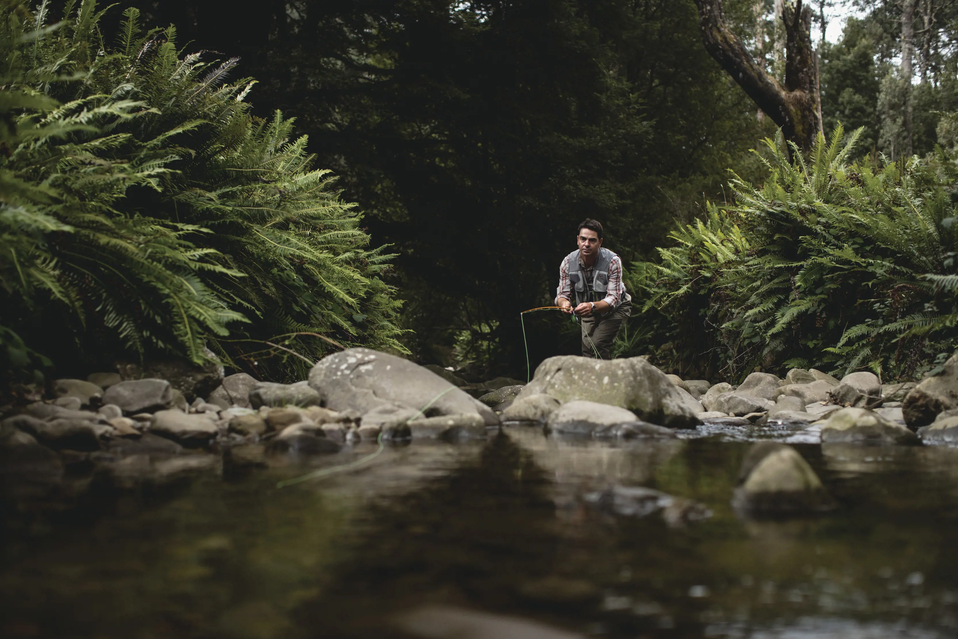 A man stands on the rocks fly fishing on the Liffey River.