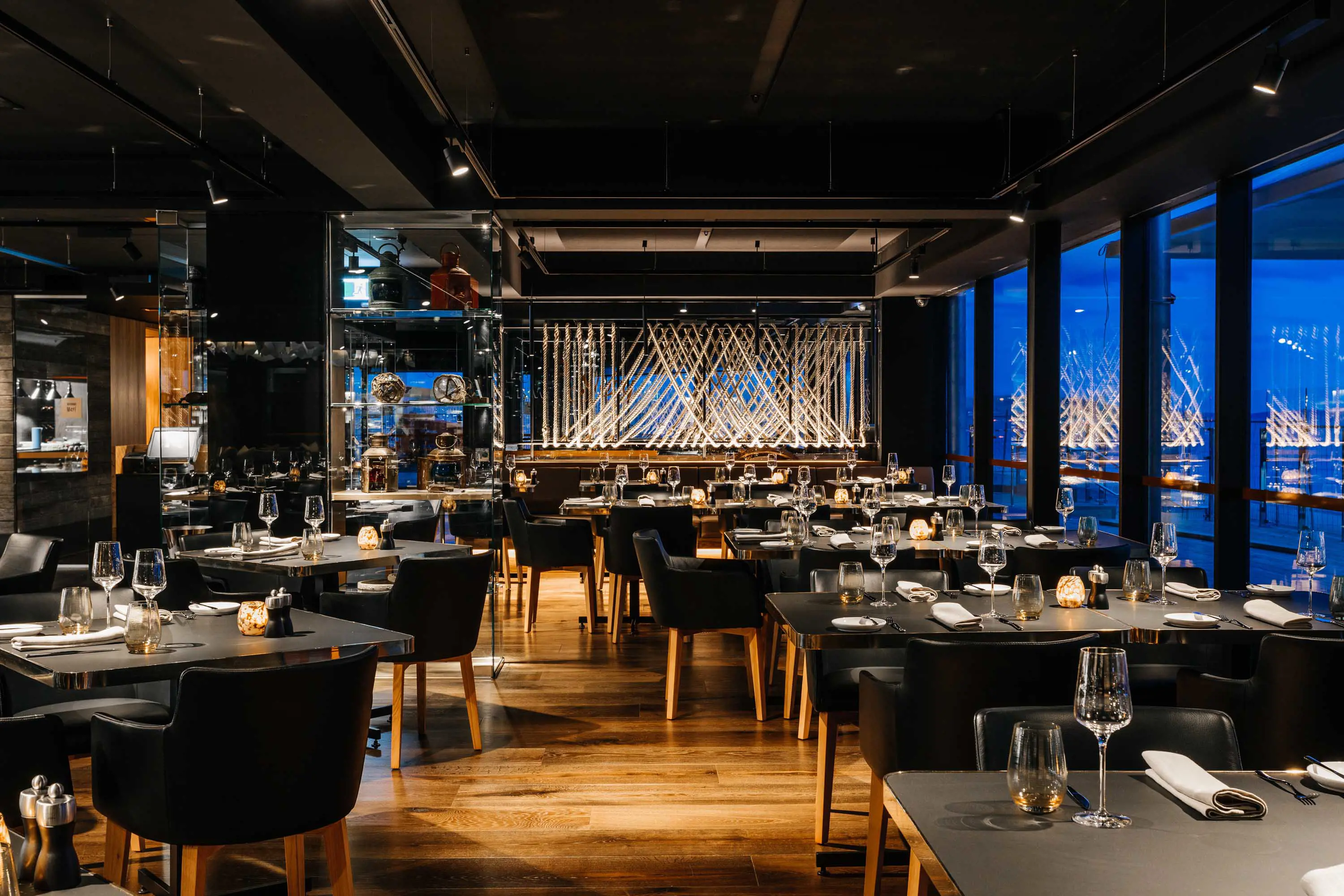 A contemporary restaurant floor with mid-century style furniture and low lighting.