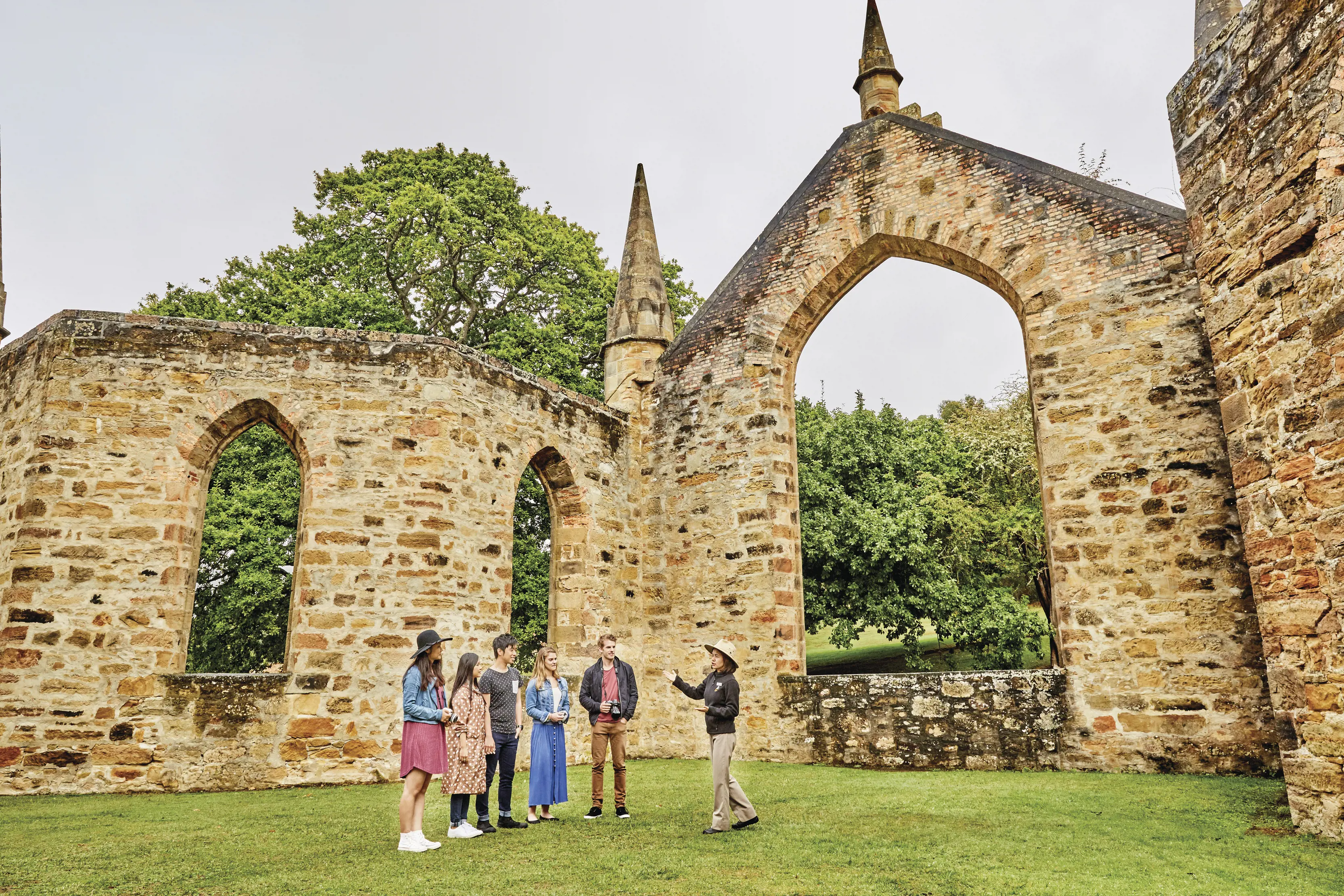 Tour guide talking to the tourists about the Port Arthur Historic Site. Old stone walls surround them.