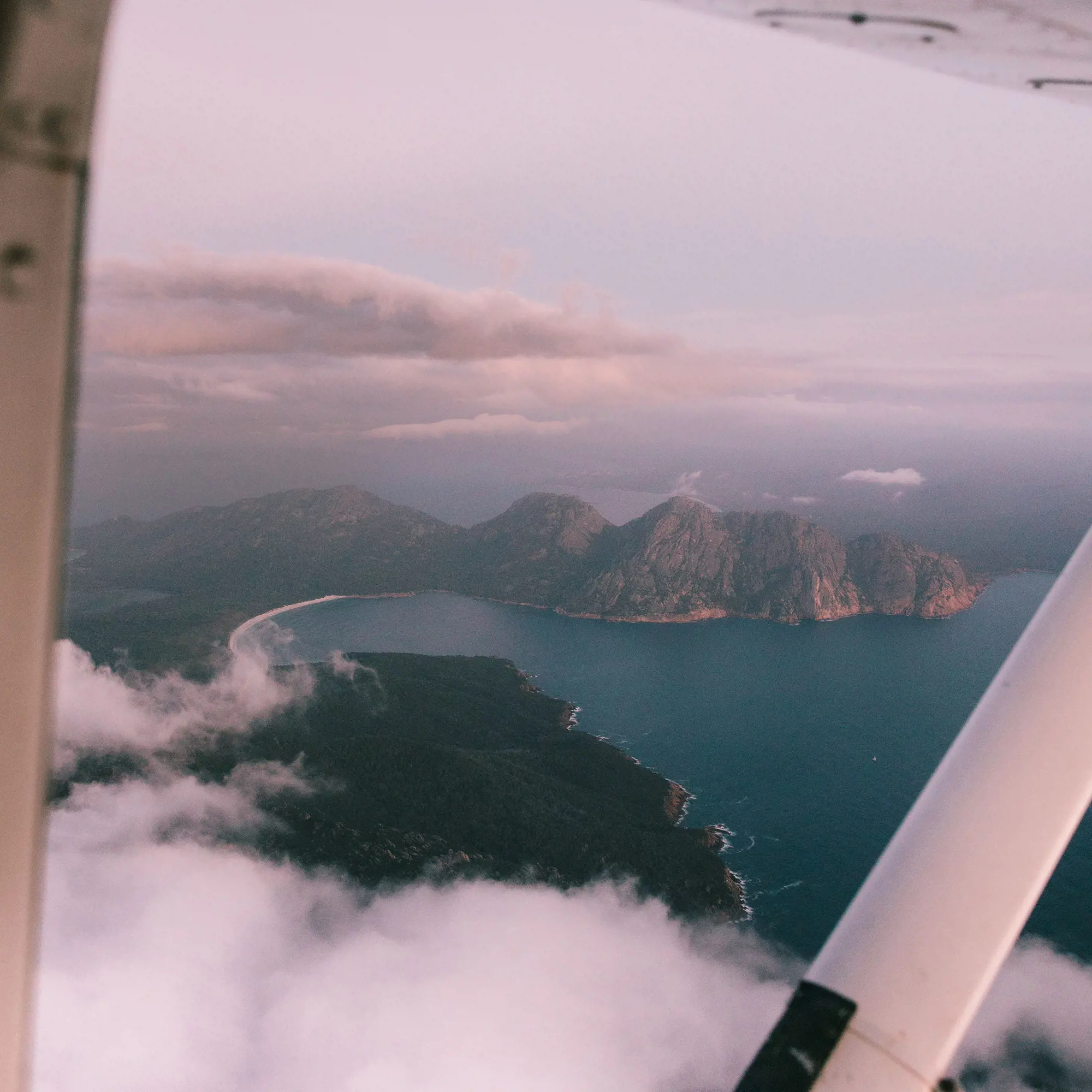 A view of Wineglass Bay, as seen from a light plane. The bay is framed as the plane flies above a cloud.