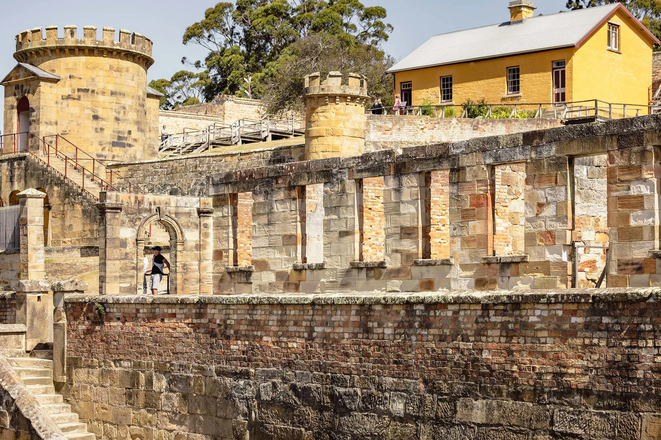 A multi-layered, sandstone historic site, featuring castle-like turrets and an old yellow building.