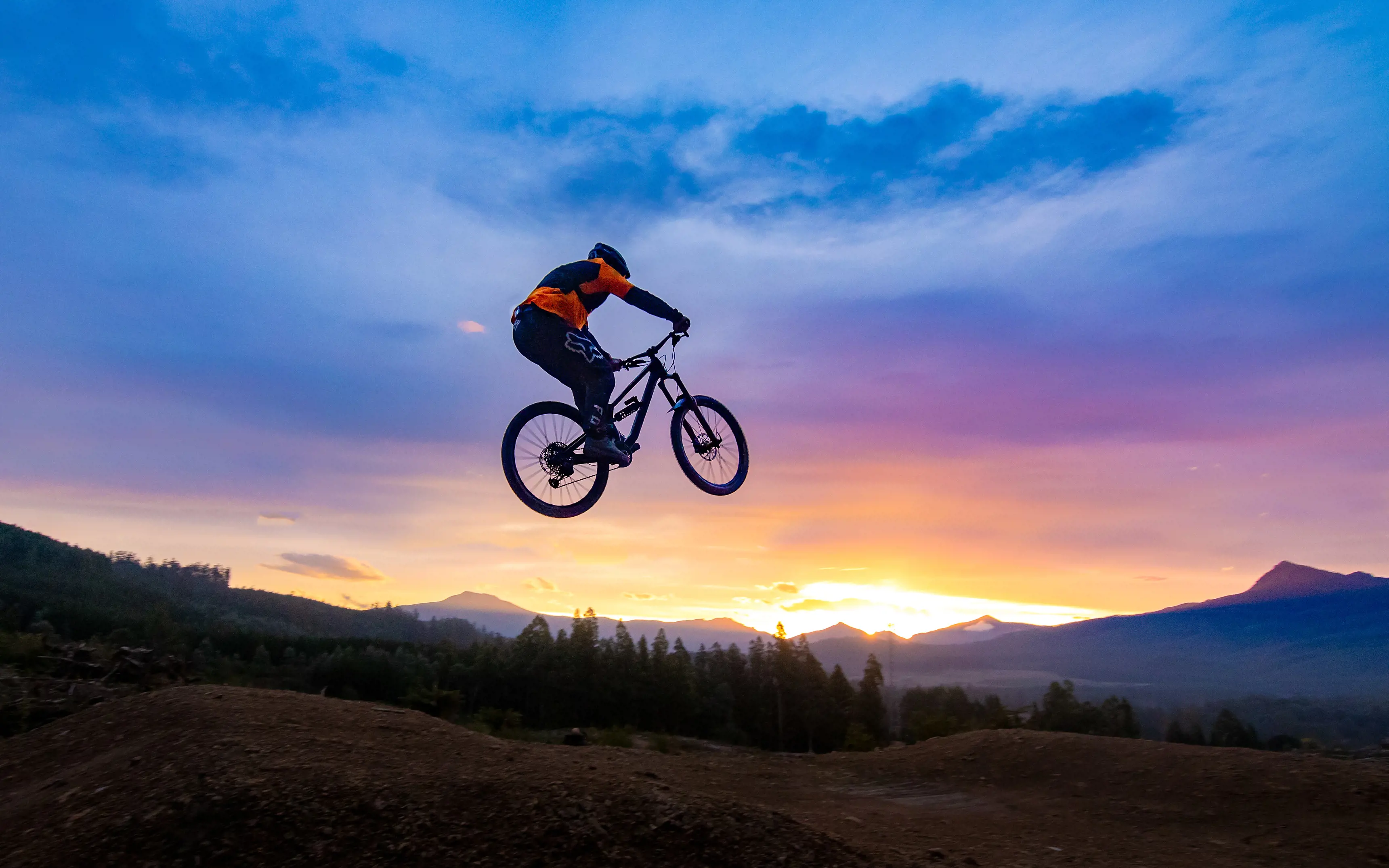 Cyclist in the air at Maydena Bike Park, with pink skies in the backdrop
