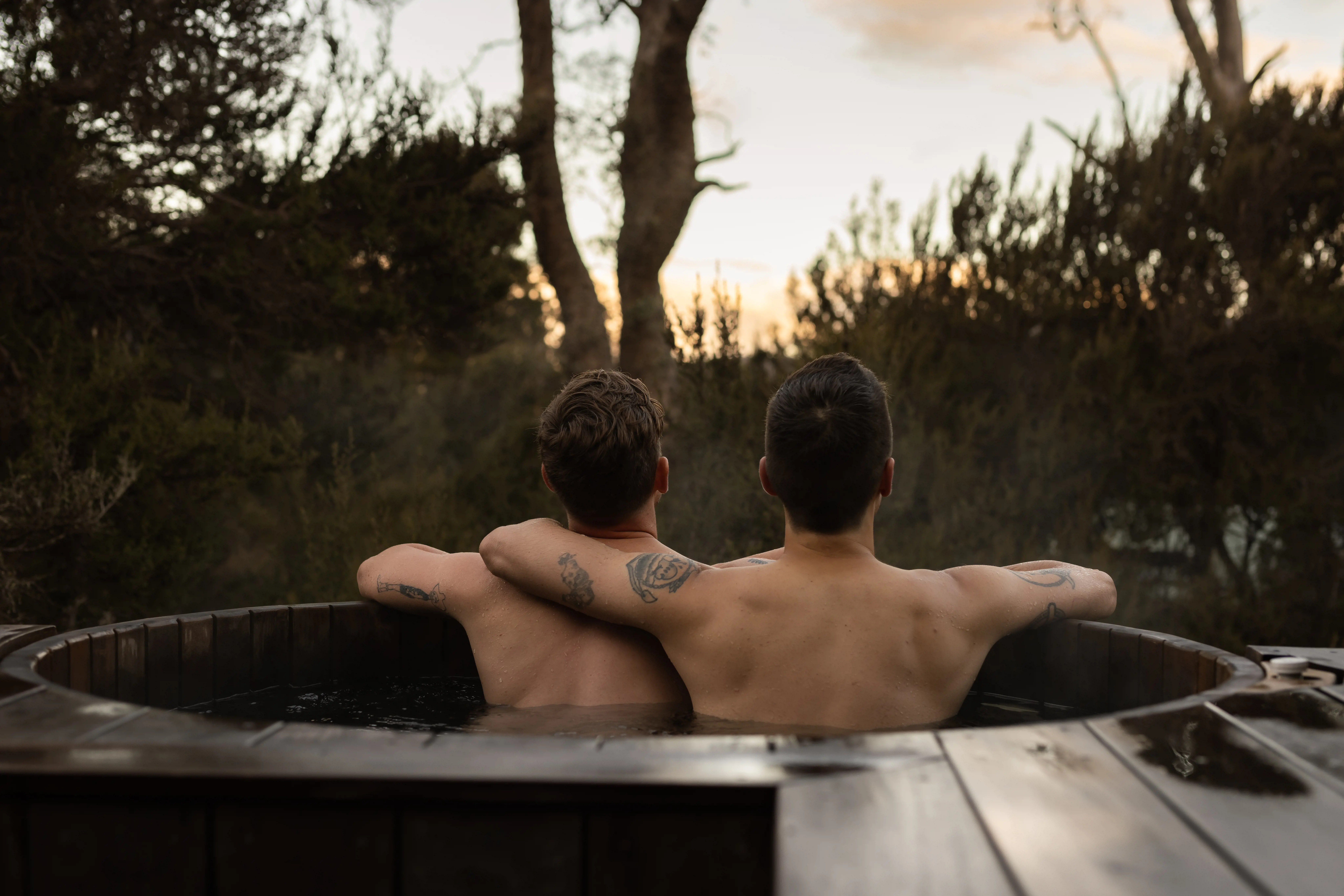 Couple relax in the steaming outdoor bath tub at Peppers Cradle Mountain Lodge. 