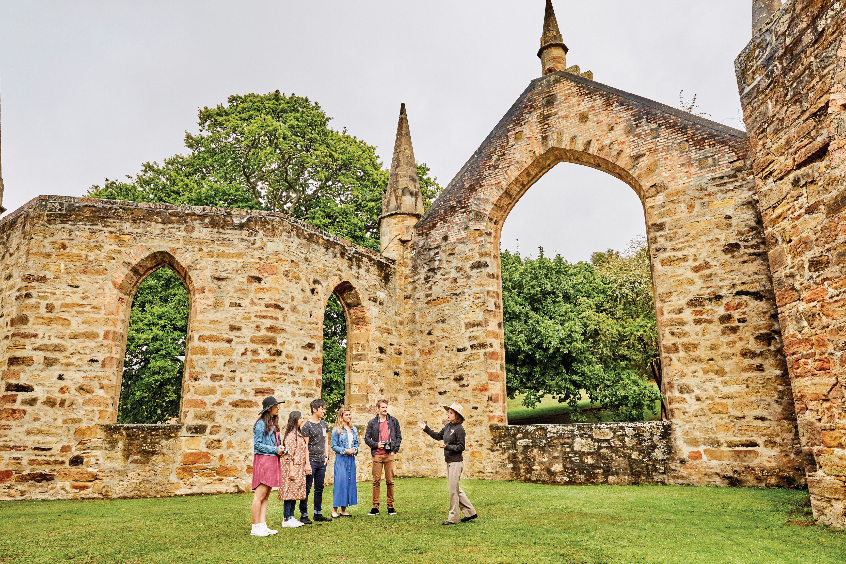 Tour guide talking to the tourists about the Port Arthur Historic Site. Old stone walls surround them.