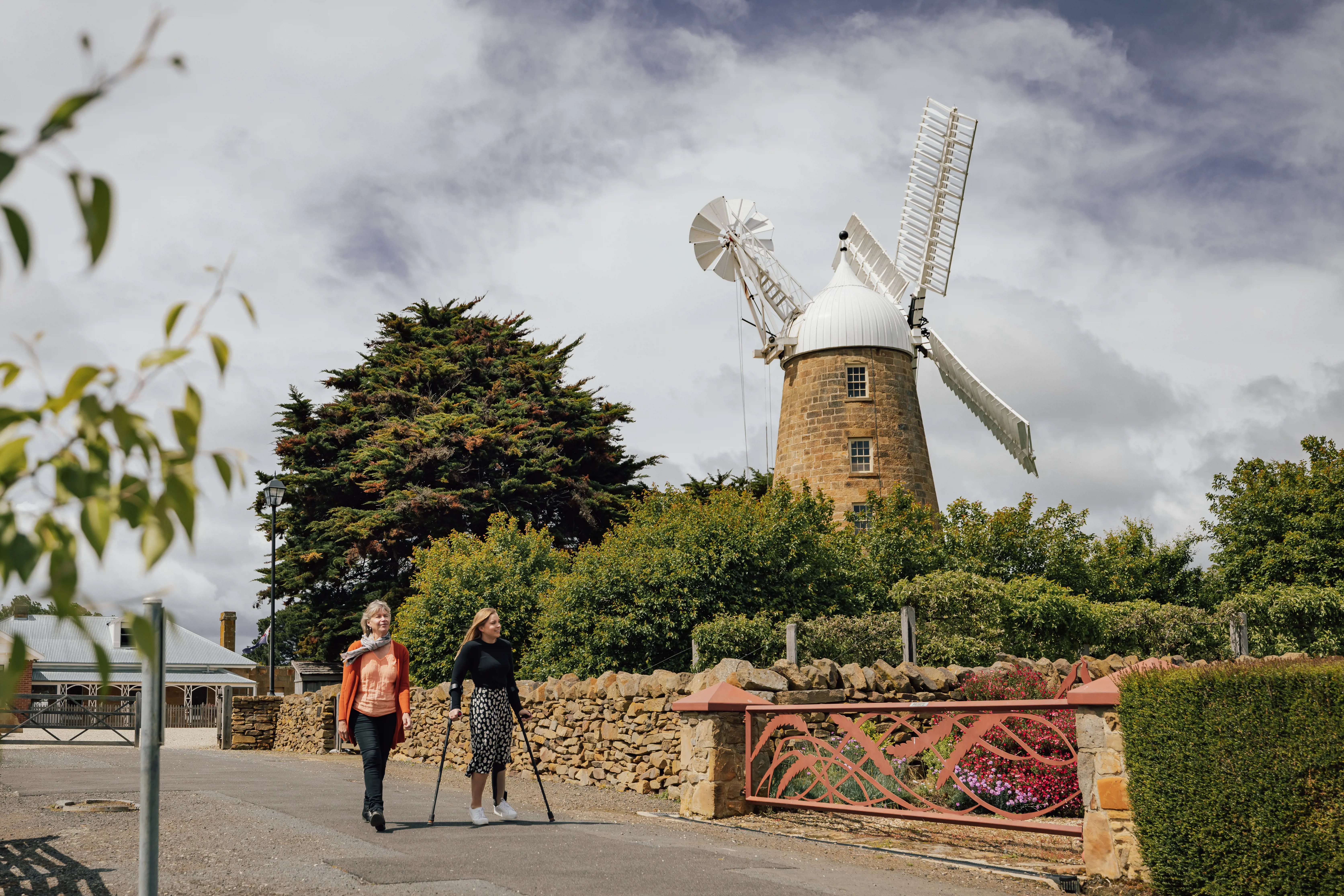 A couple of people walking along the road with Callington Mill displayed in the background