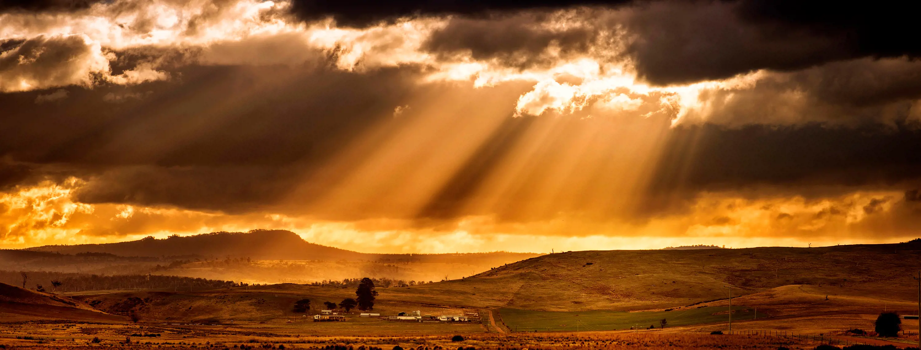 The sun setting over the beautiful farm on the Midlands Highway. The sun shining through the clouds.