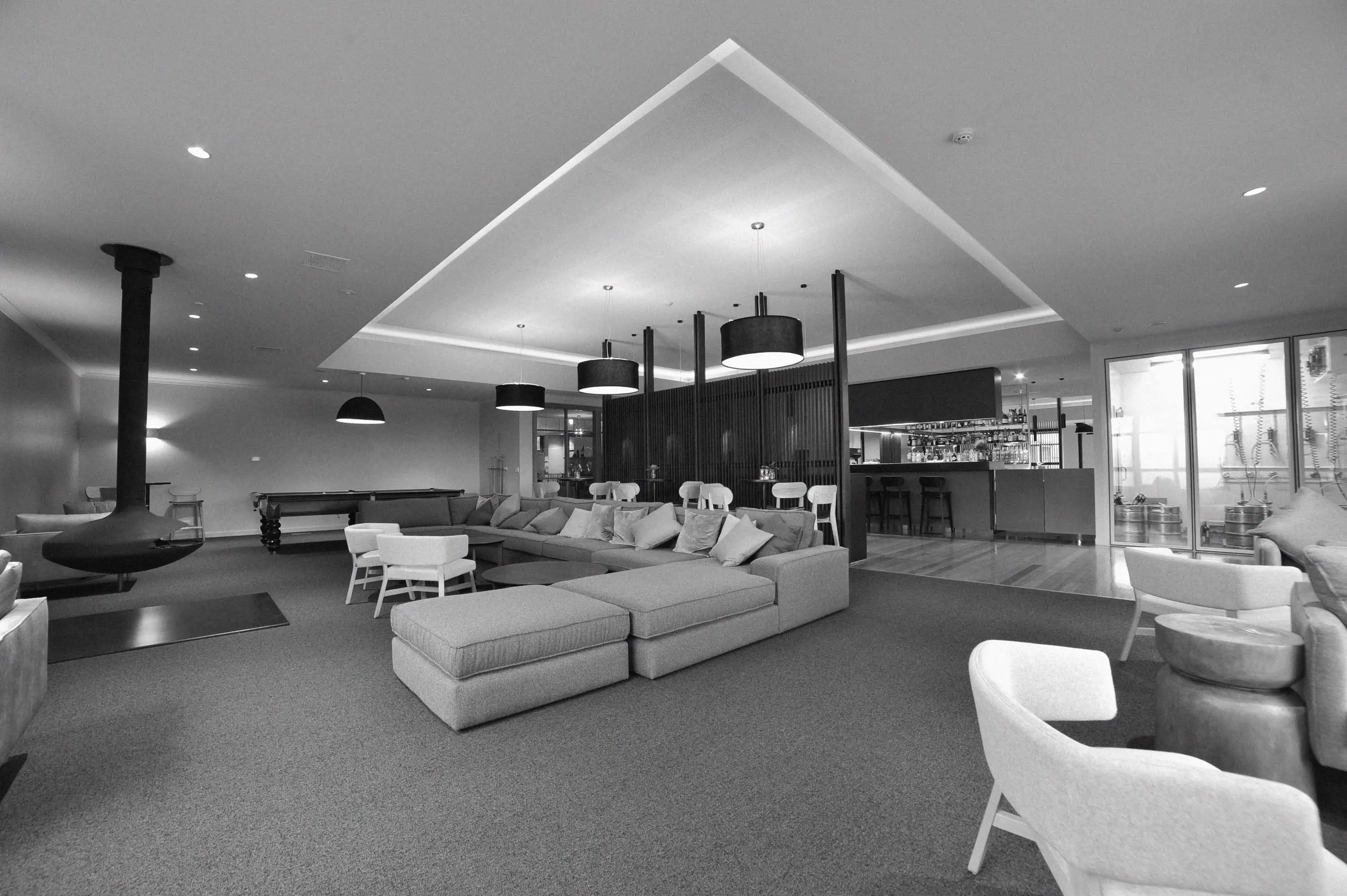 A modern hotel foyer with large couches surrounding a suspended metal fireplace.