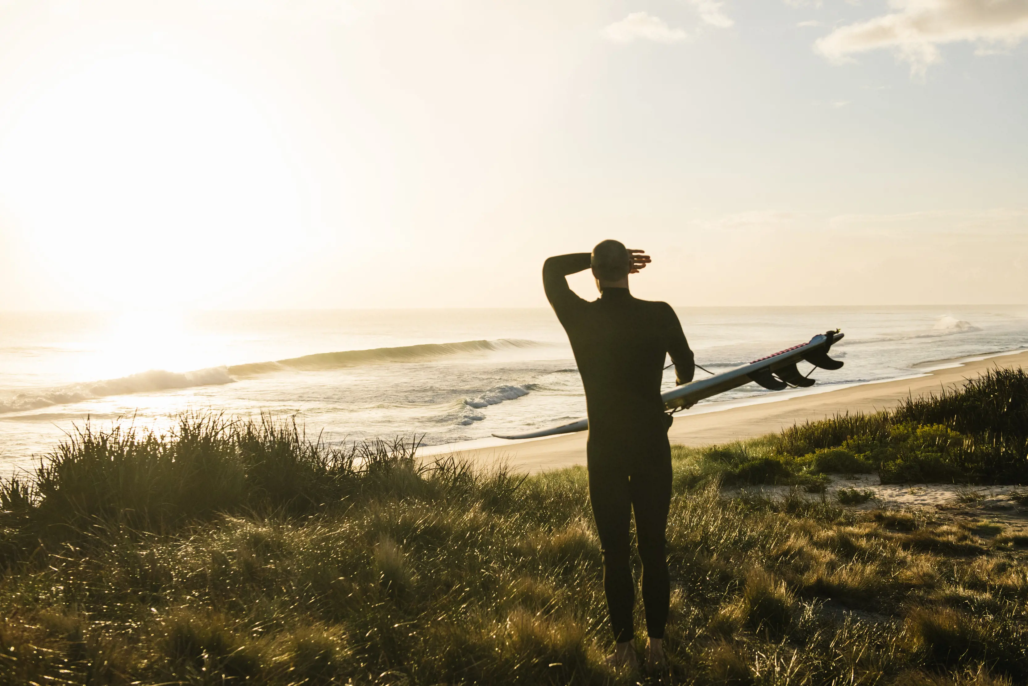 Surfer with his board checking out the surf at Martha Lavinia Beach, King Island, on sunrise.