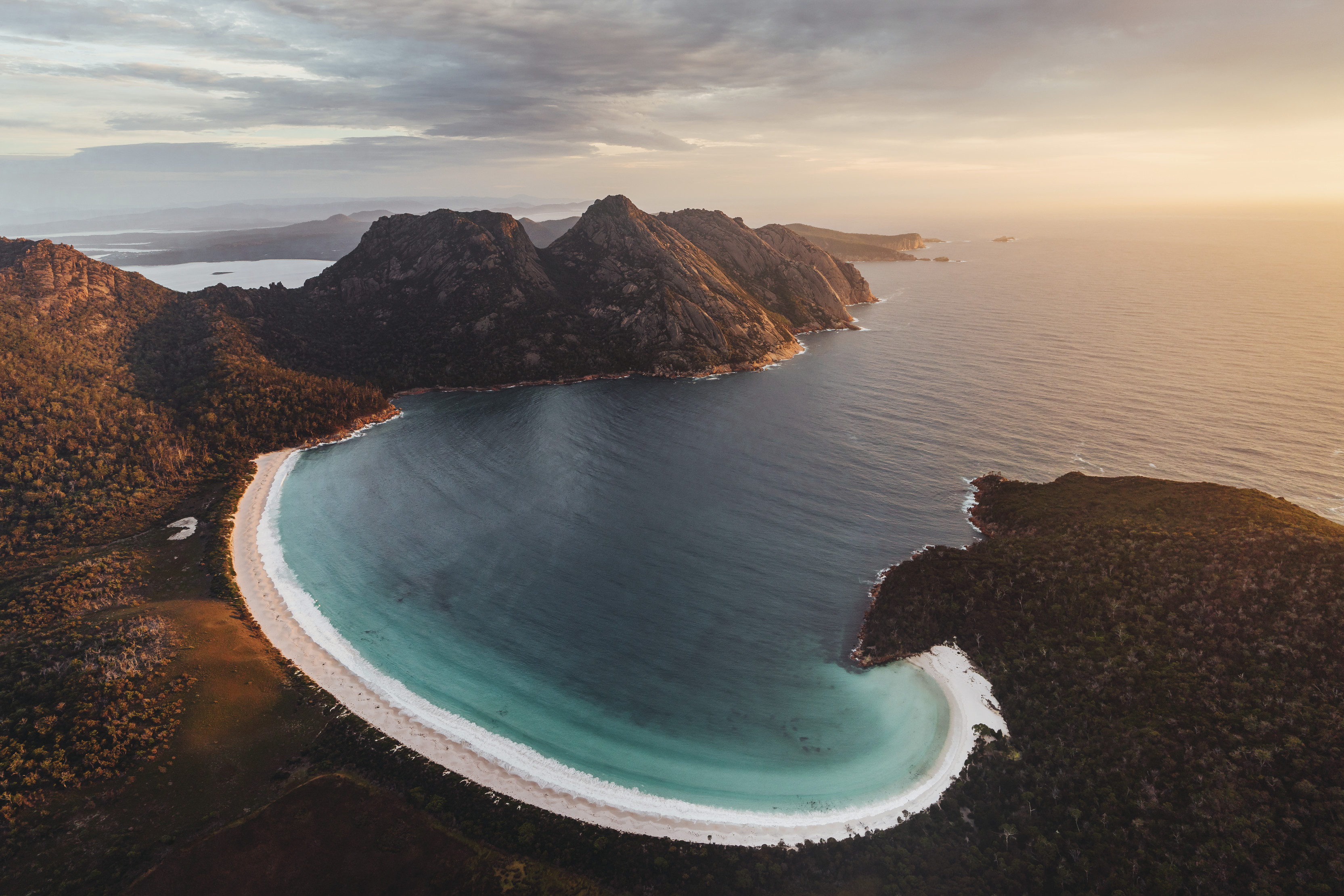 Ariel of Wineglass Bay with the run relfecting orange tones onto the water.