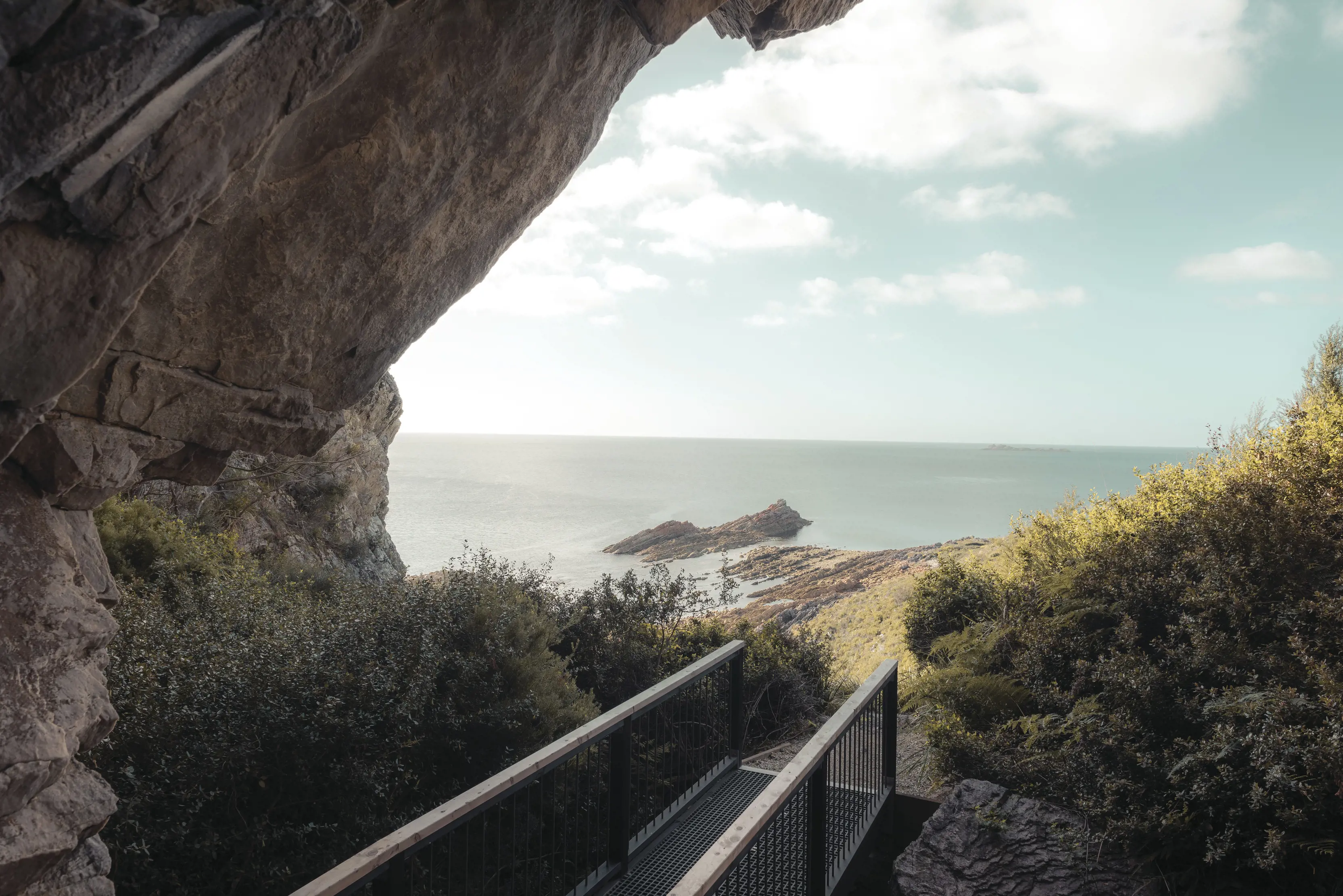 Large rocks scale across the top left of image with a footpath underneath, leading to the coastline, at Banksia Grove, Rocky Cape National Park.