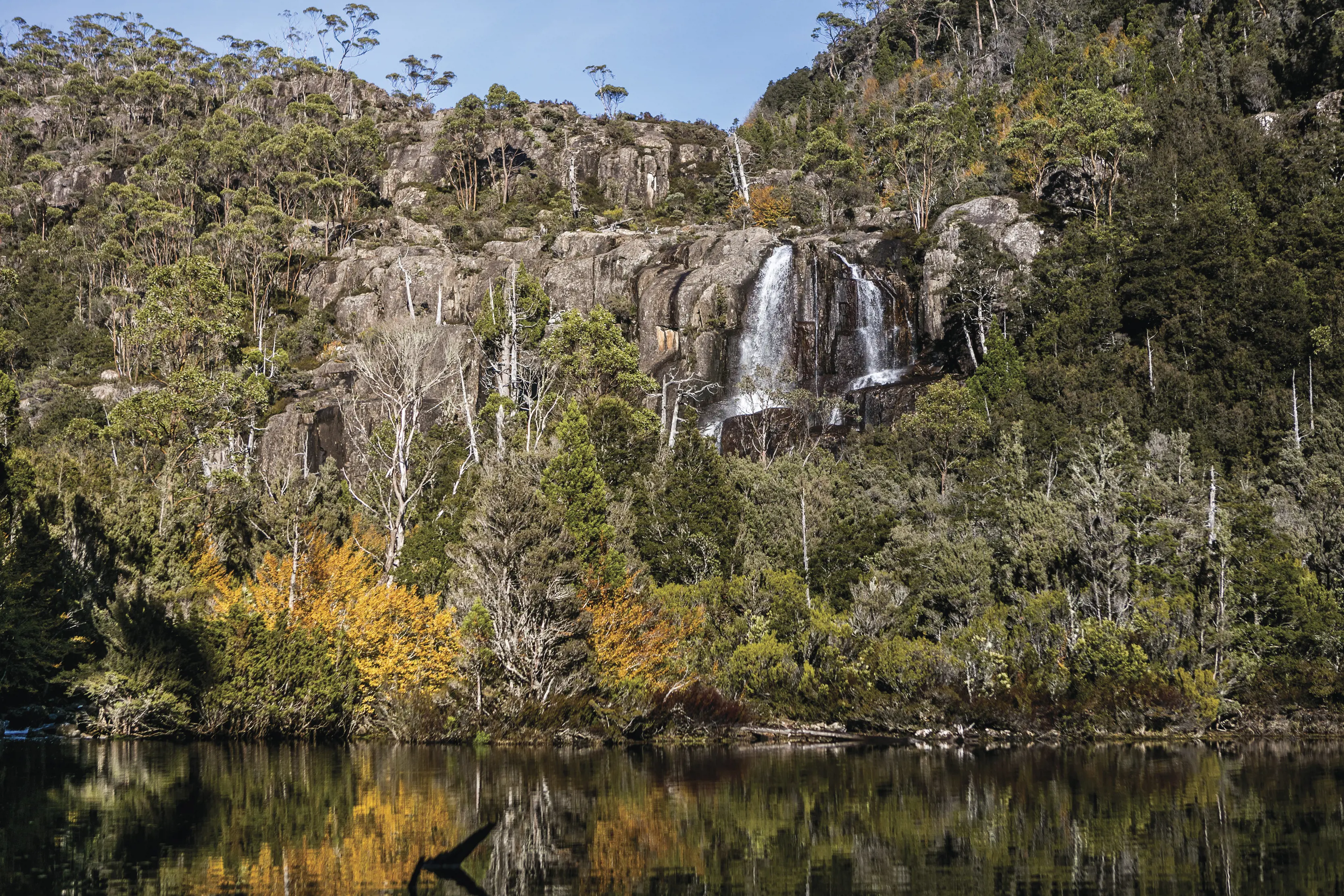 Spectacular image of Grail Falls that is surrounded by lush, colourful forest and a calm creek at the foreground.