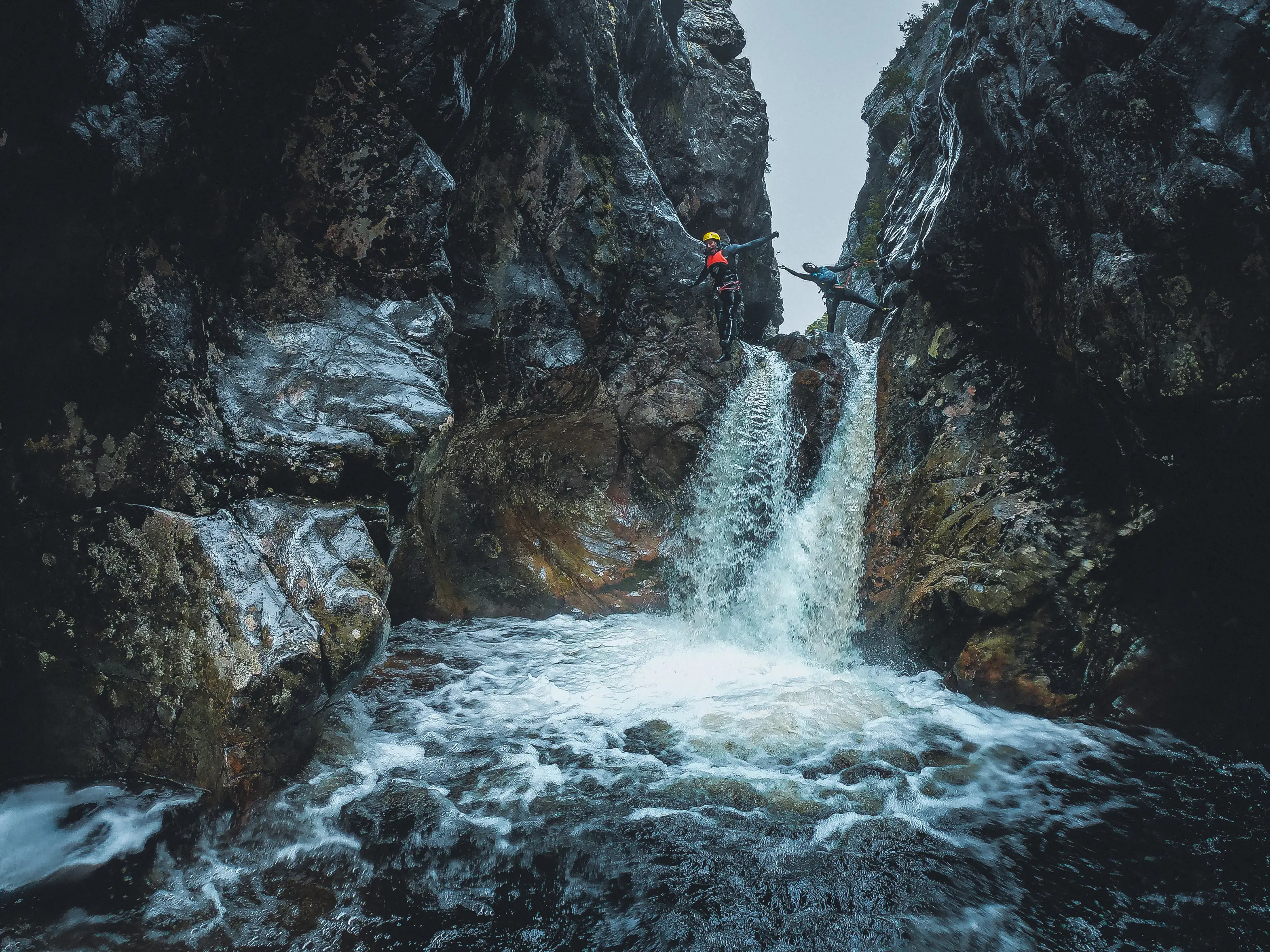 Two people abseiling down a waterfall, posing for the photo, within Cradle Mountain Canyons.