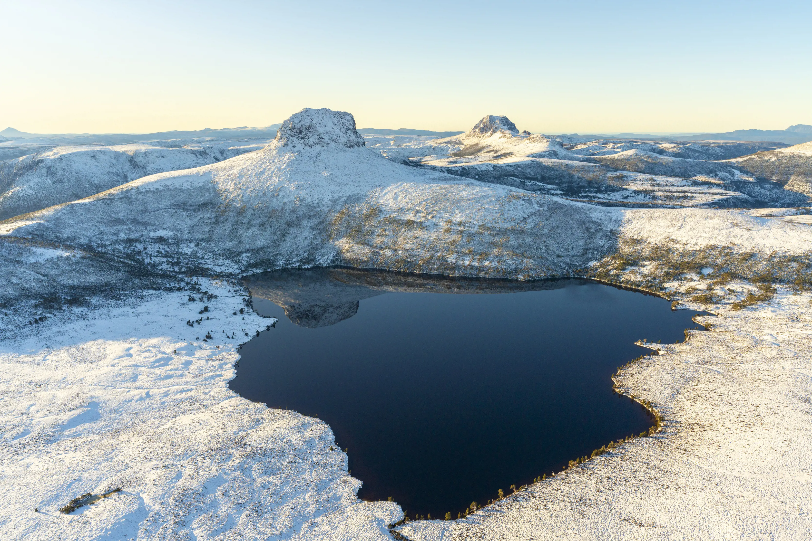 Crystal clear aerial image of Barn Bluff and Lake Will on a cool, winter's day. Ice and vibrant blues fill the scene.