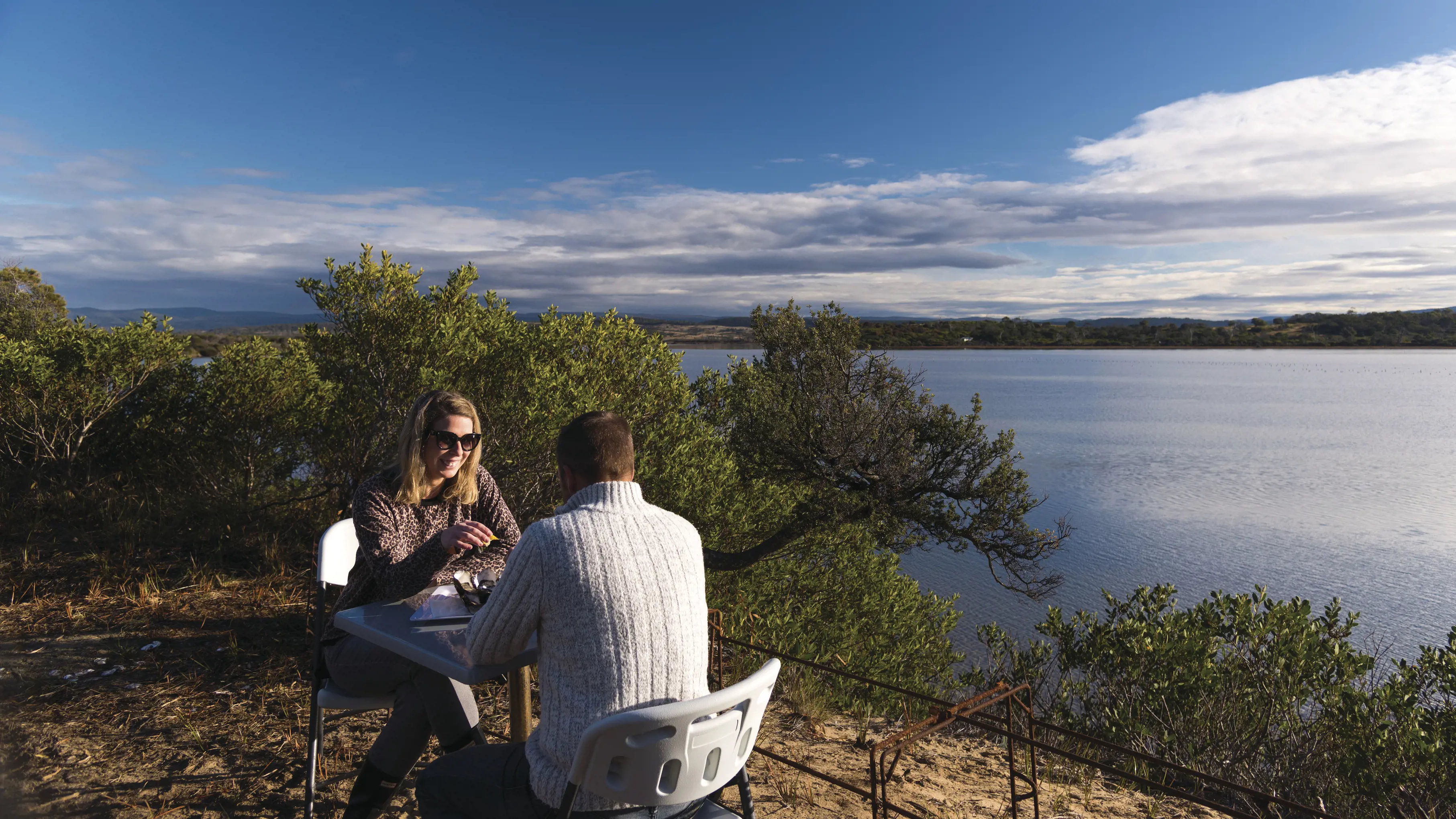 Couple sitting outside, enjoying oysters at Melshell Oysters Farm Gate.