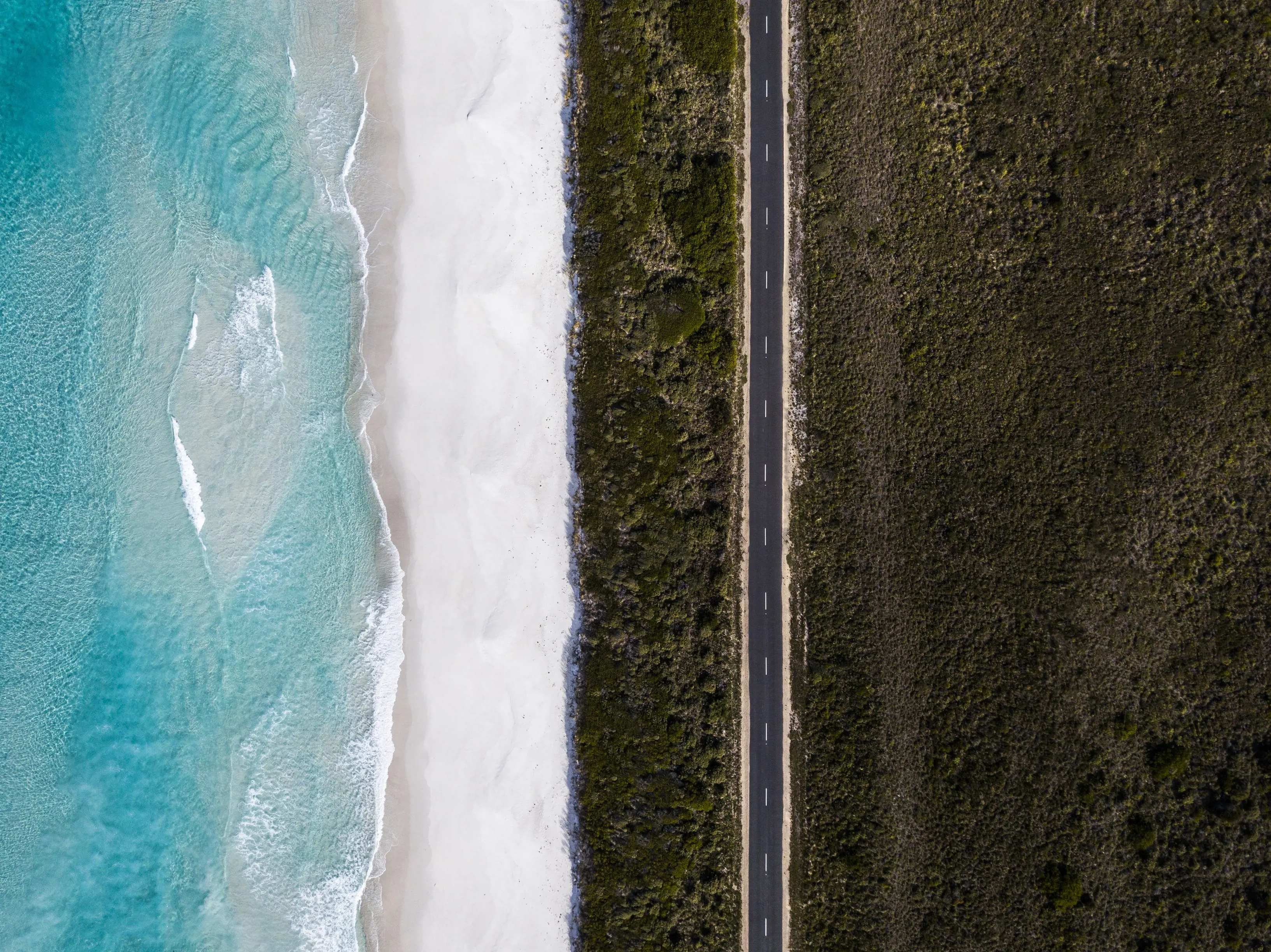 An incredible aerial view of the Road to Bicheno, with the stunning shoreline and ocean on one side and lush bushland on the opposite.
